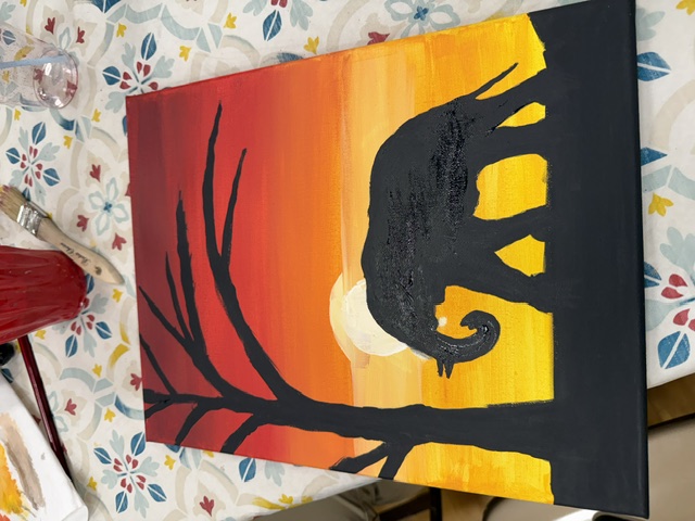 A finished painting of an elephant walking beneath a tree at sunset