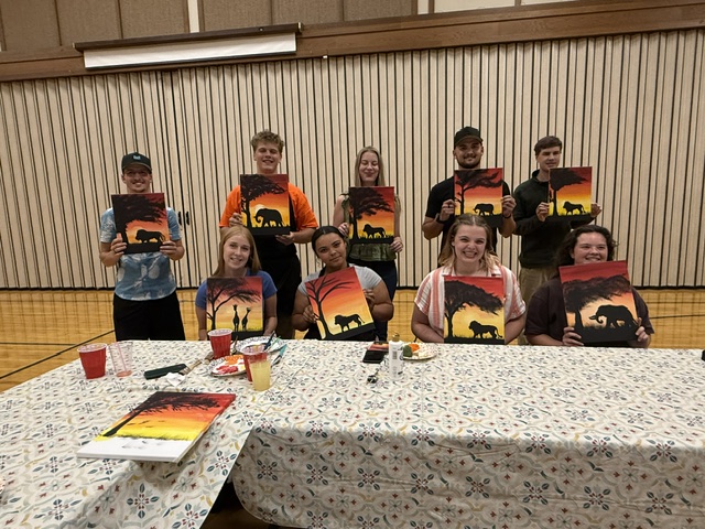 Painters holding up their finished sunset canvases at the end of the evening