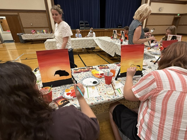 Friends painting side by side at a long table