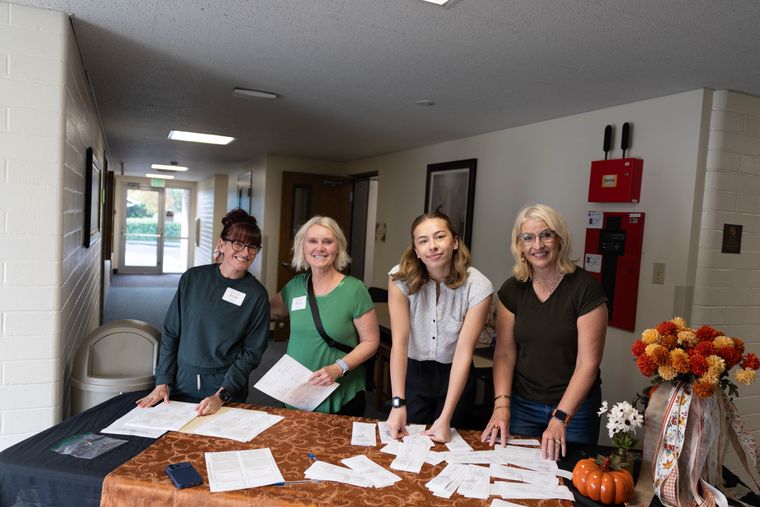 Four members of the welcoming committee smiling behind the registration table