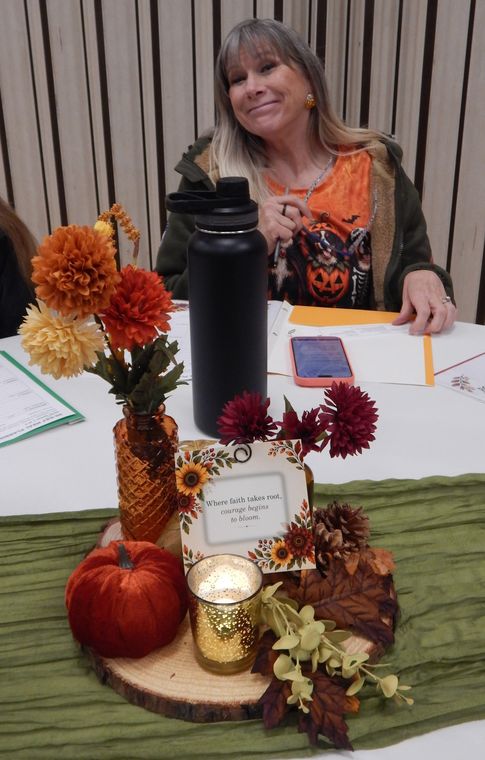 A smiling sister seated at a table with a fall centerpiece