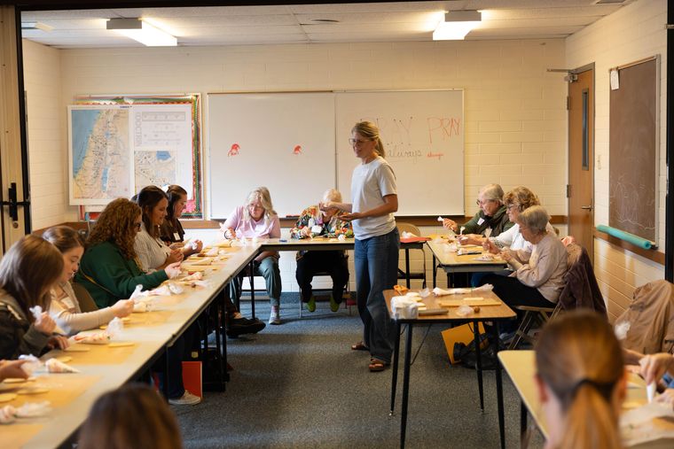 Tia Davidson standing at the front of a classroom of sisters decorating cookies