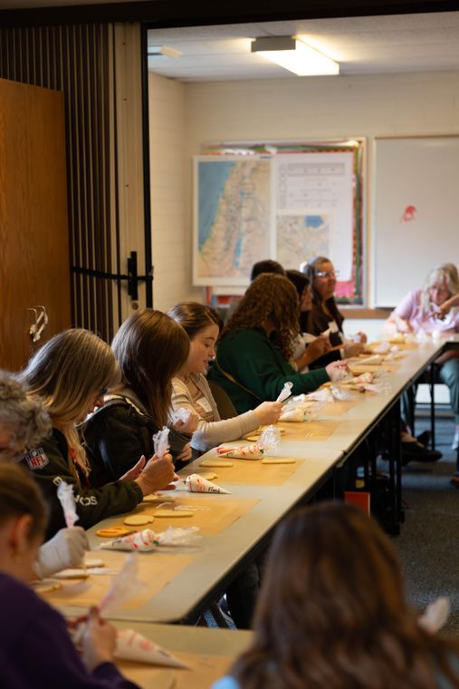 Sisters along a long table piping icing onto sugar cookies