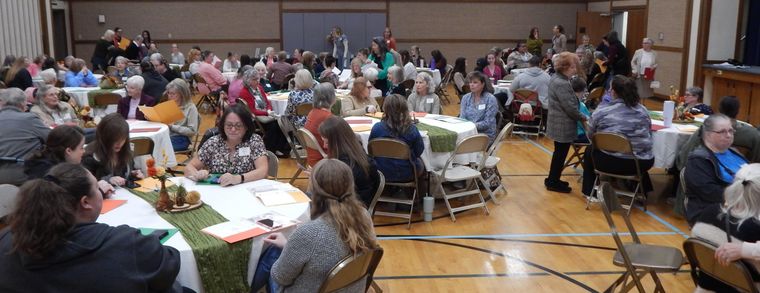 A wide view of the cultural hall filled with sisters at round tables