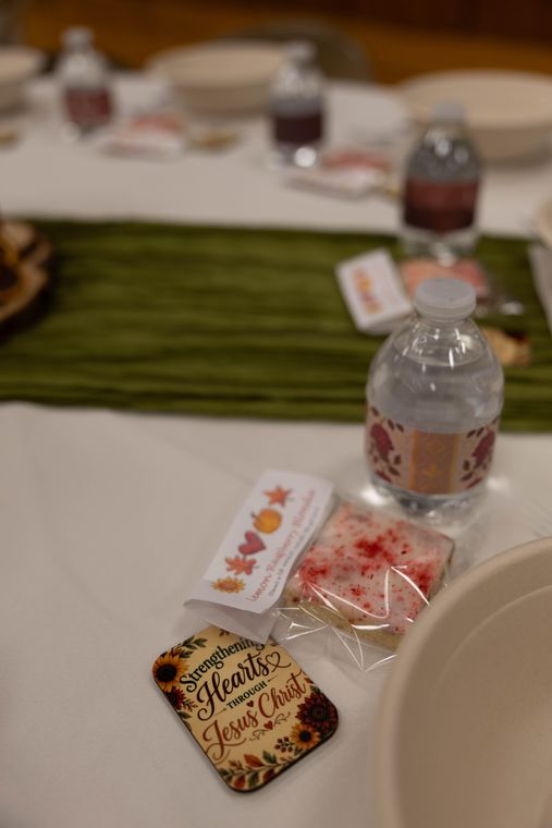 A water bottle and a Strengthening Hearts through Jesus Christ keepsake at a place setting