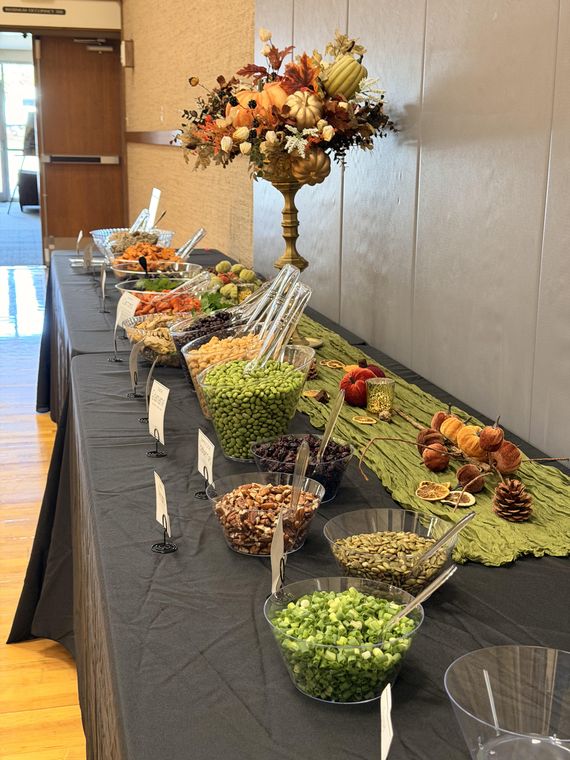 The luncheon buffet line with bowls of toppings beneath a fall floral arrangement
